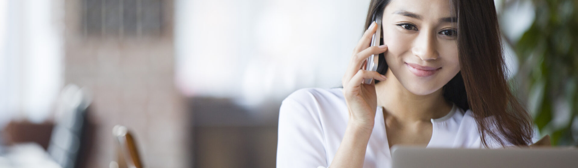 Uma mulher numa mesa de trabalho fazendo uma ligação telefônica para cobrar um cliente