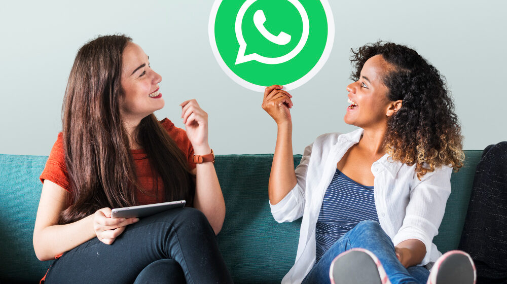 Duas mulheres sorrindo olhando para o símbolo do WhatsApp